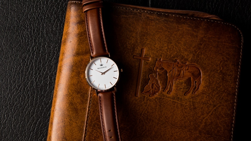 Mens rose gold case, brown leather strap watch on case that shows Christian cross.