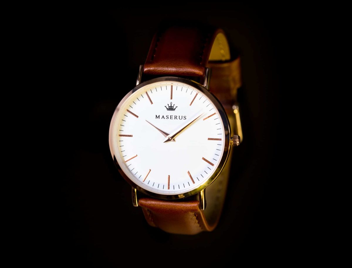 Product image one of mens rose gold case, brown leather strap watch against black.