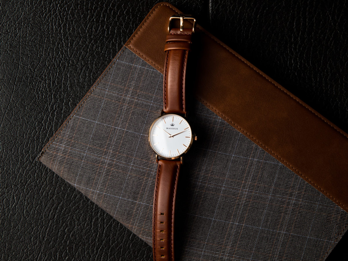 Product image two of mens rose gold case, brown leather strap watch on fabric.