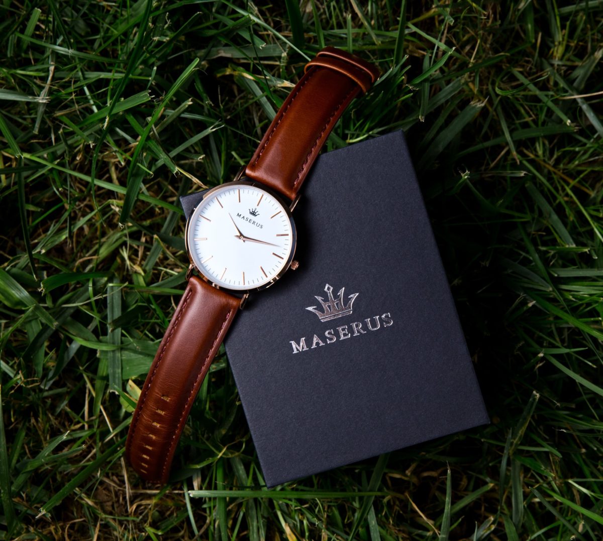 Product image three of mens rose gold case, brown leather strap watch on box.